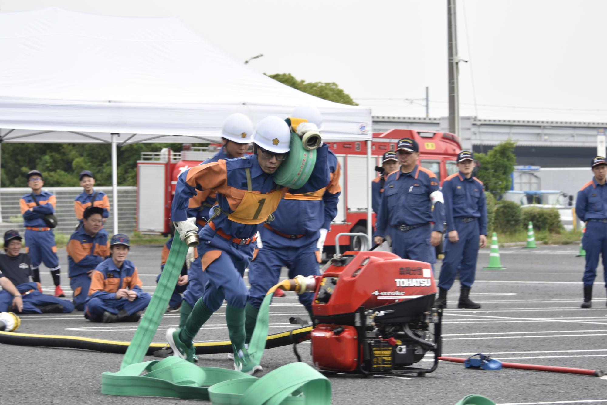 操法大会でホースを担いで走る森岡分団員